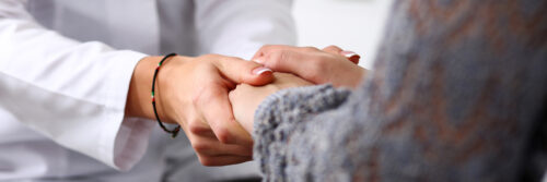 Friendly female doctor hold patient hand in office during reception