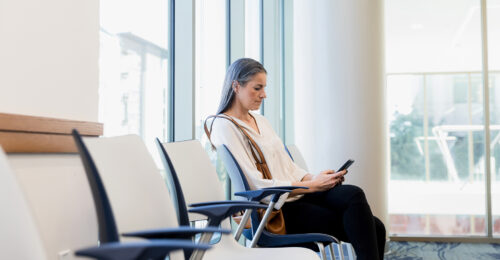 Woman uses smart phone while sitting in waiting room