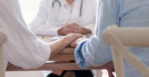 Mature couple holding hands at a doctors office.