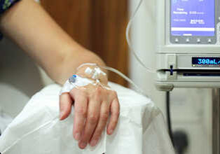 Infusion pump feeding IV drip into patients arm focus on needle