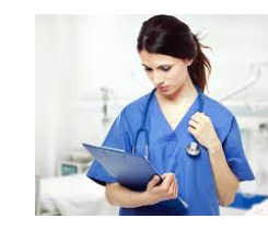 A woman in scrubs looks at a clipboard while draping a stethoscope around her shoulders