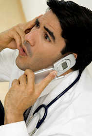 Editorial Photo: A doctor looking highly stressed holds a flip-phone to each ear